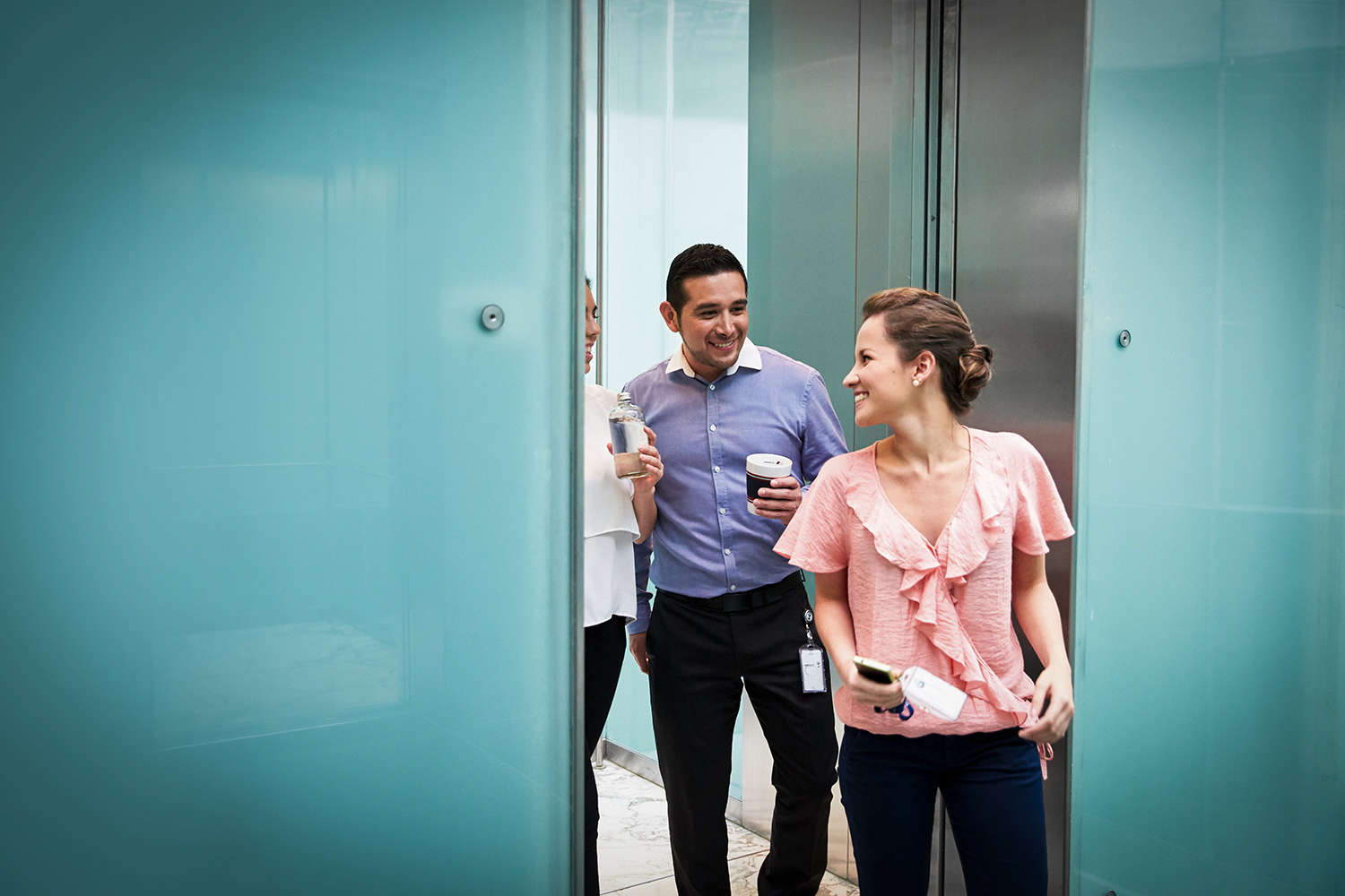 The image shows a group of people stepping out of a lift.