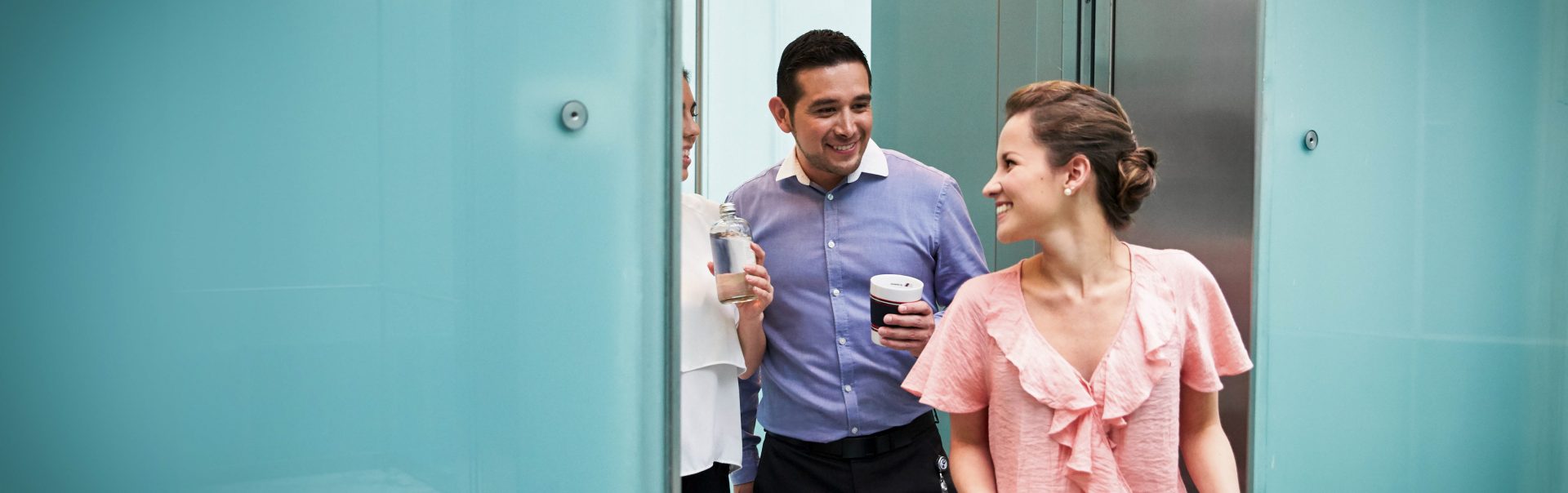 The image shows a group of people stepping out of a lift.