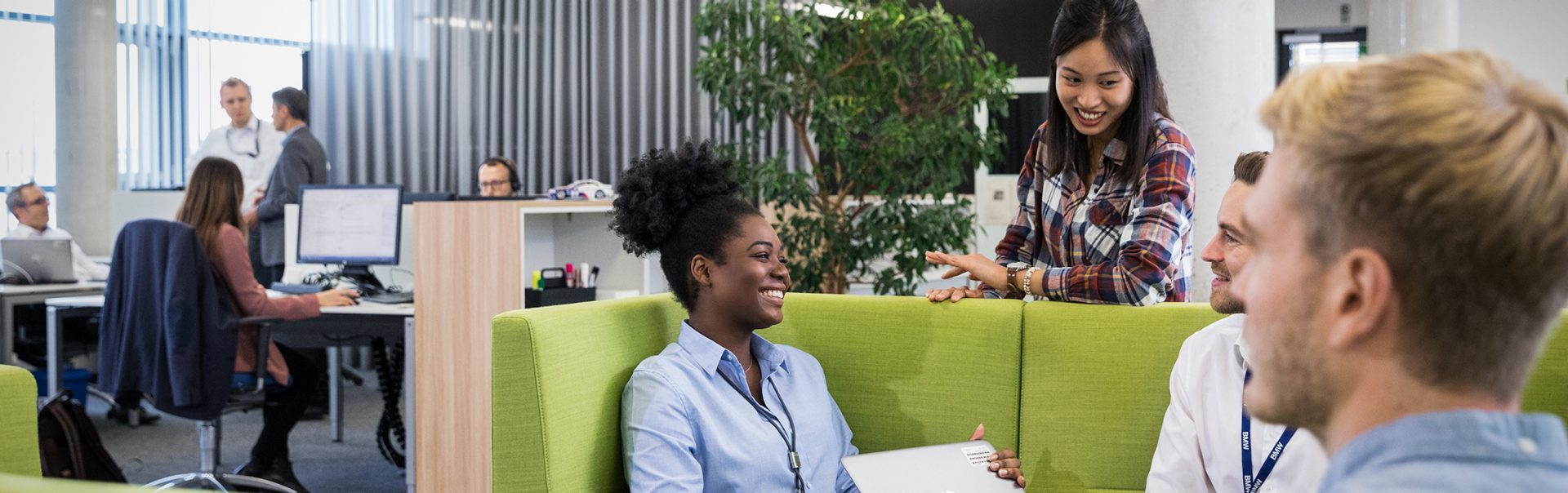 The image shows two women and two men having a chat in a BMW office.