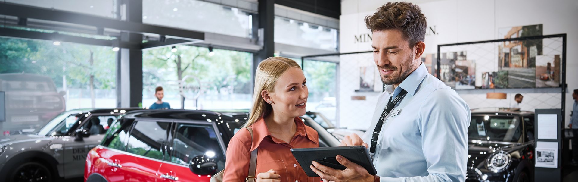 "The picture shows a BMW sales and distribution employee explaining something to a customer on a tablet.	"
