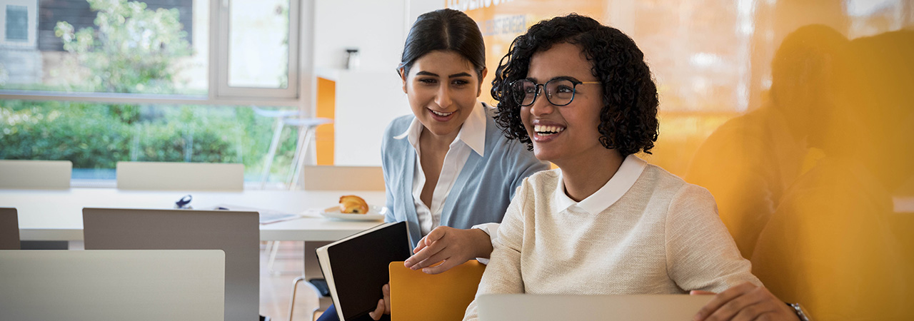 The picture shows two laughing young women representing the company culture at BMW.