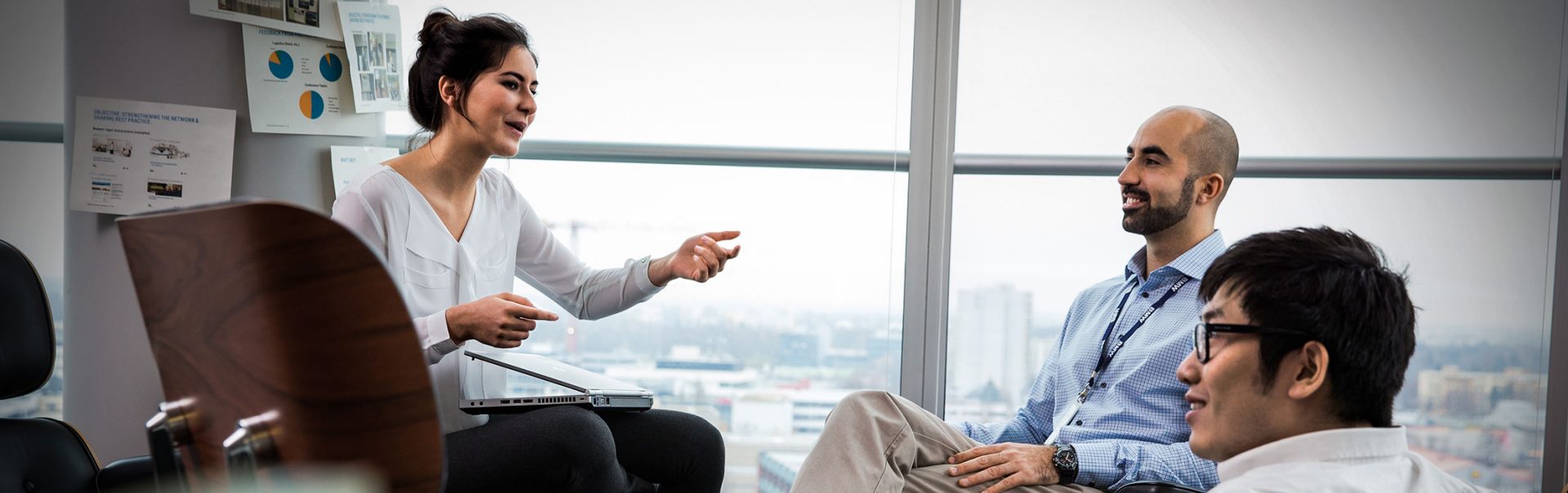 We see three young BMW employees having an animated conversation in a modern office.
