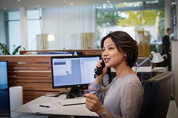 A woman who works in service and administration is on the phone answering some work-related questions.