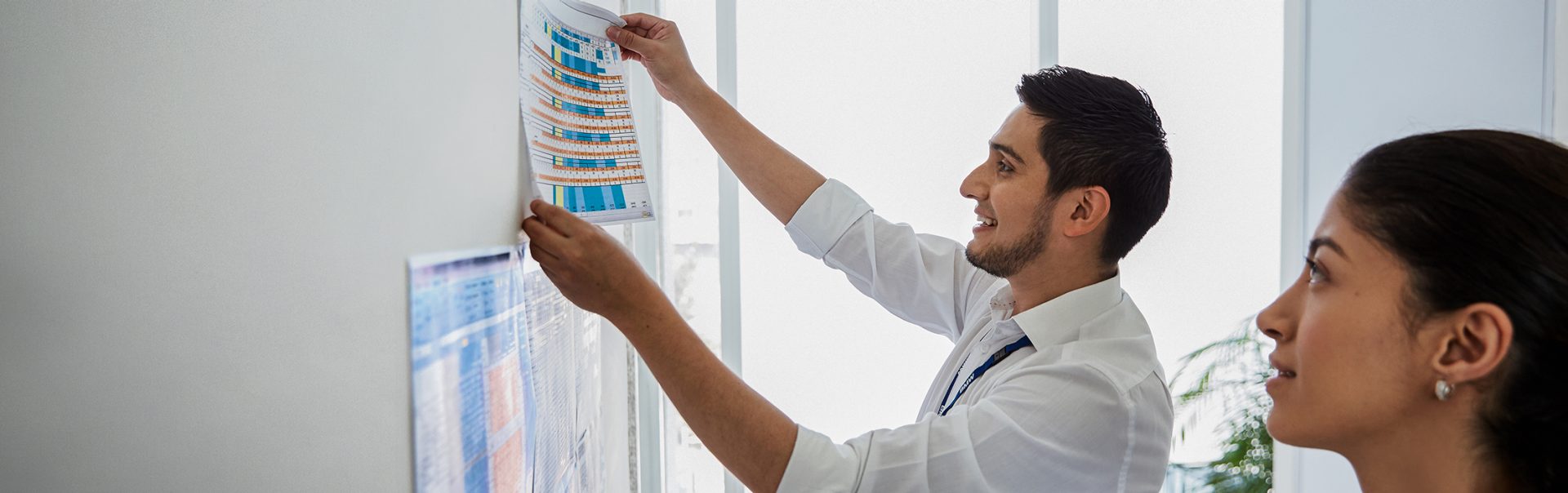 The picture shows two BMW employees working in sustainability and environment putting up charts on a whiteboard.