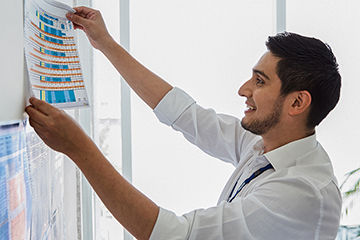 The picture shows two BMW employees working in sustainability and environment putting up charts on a whiteboard.