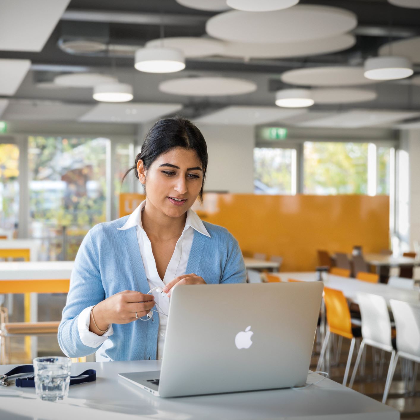 The image shows a BMW employee working with her laptop in a BMW office.