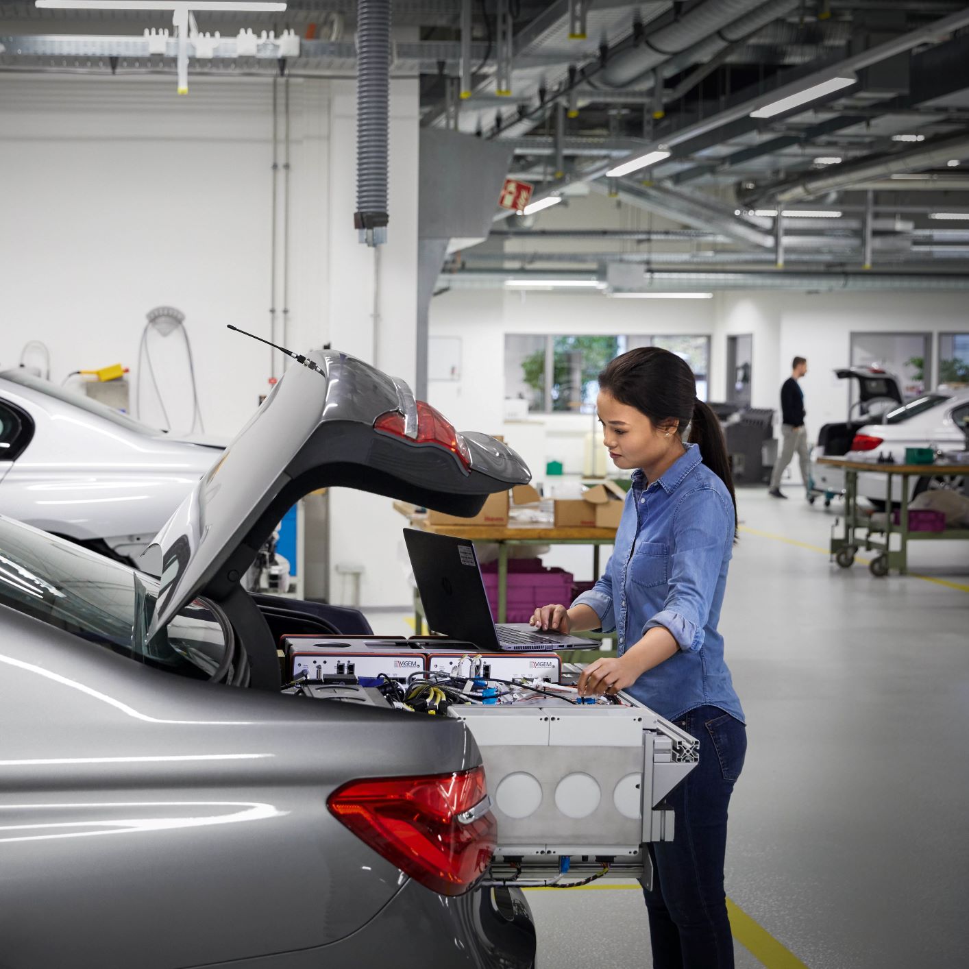 The image shows a BMW employee analysing vehicle data.