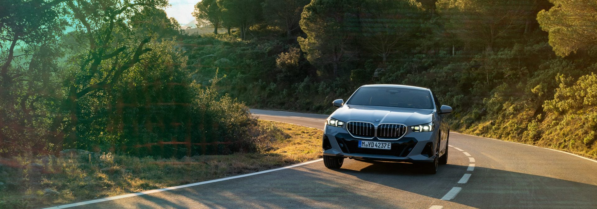BMW i5 auf einer Landstraße in der Natur.