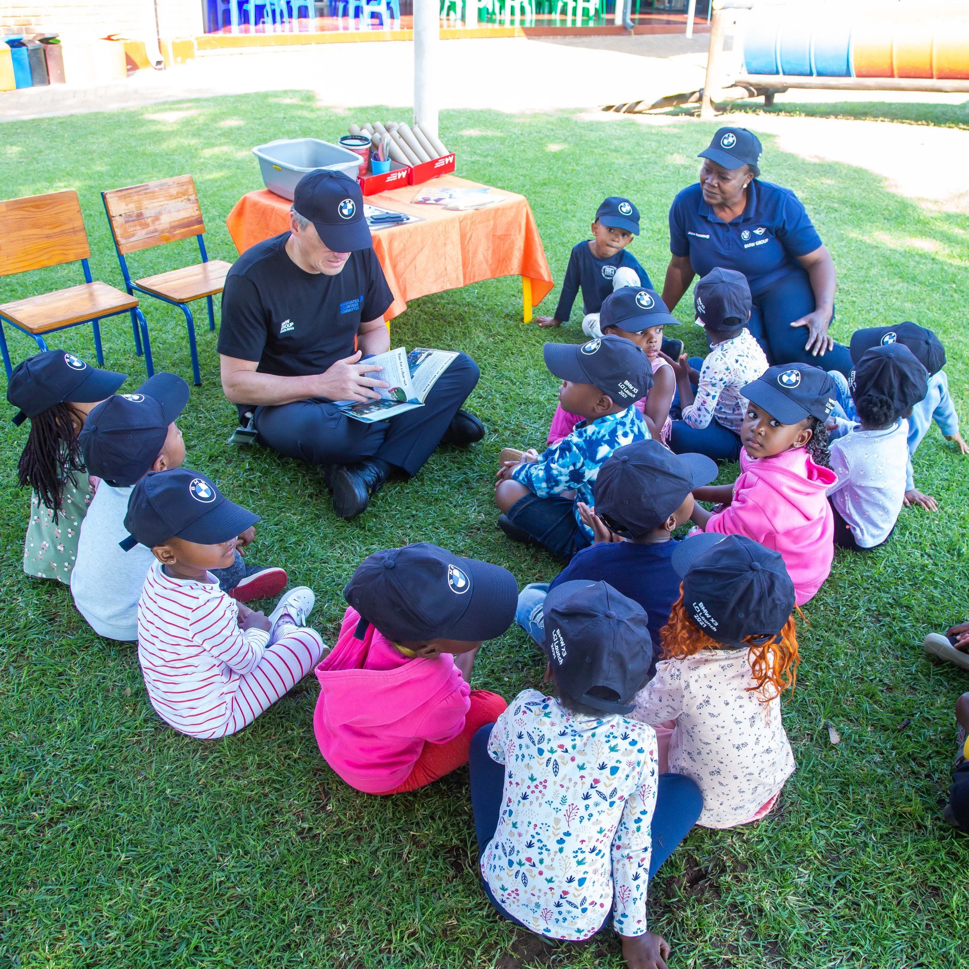 BMW Group South Africa employees reading to young children outside. 