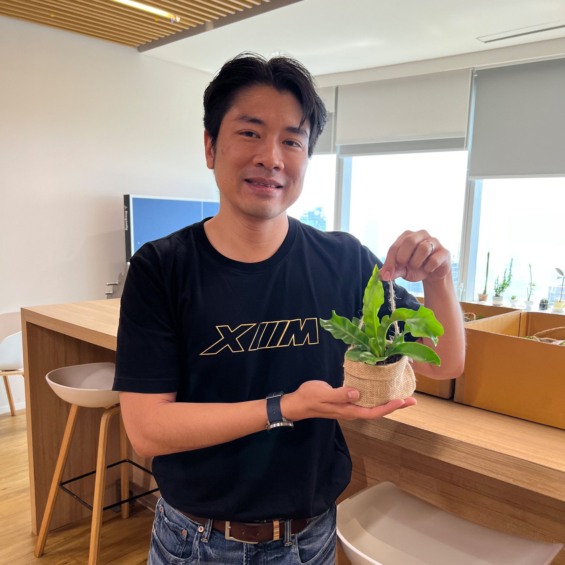 BMW Group Thailand employee holding a plant.