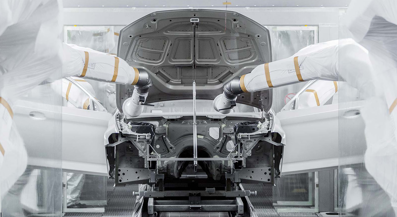 Das Foto zeigt zwei Roboterarme in einer Produktionsstraße von BMW beim Zusammenbau einer Karosserie.