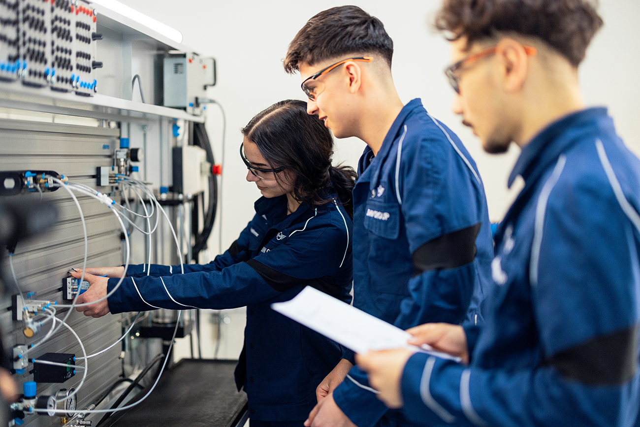 Drei Lehrlinge bei der Arbeit an einem elektronischen Schaltkasten