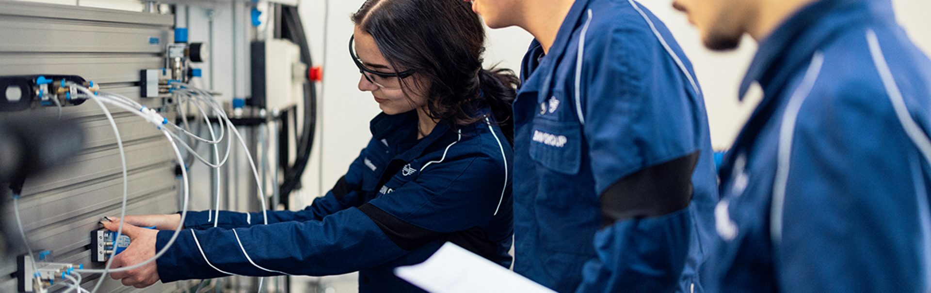 Drei Auszubildende arbeiten an einer Maschine im Werk Steyr.