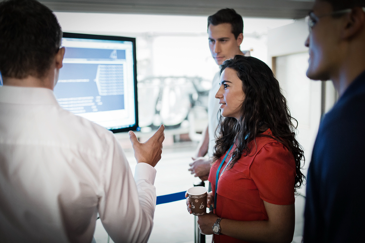Four professionals are analysing data on a screen