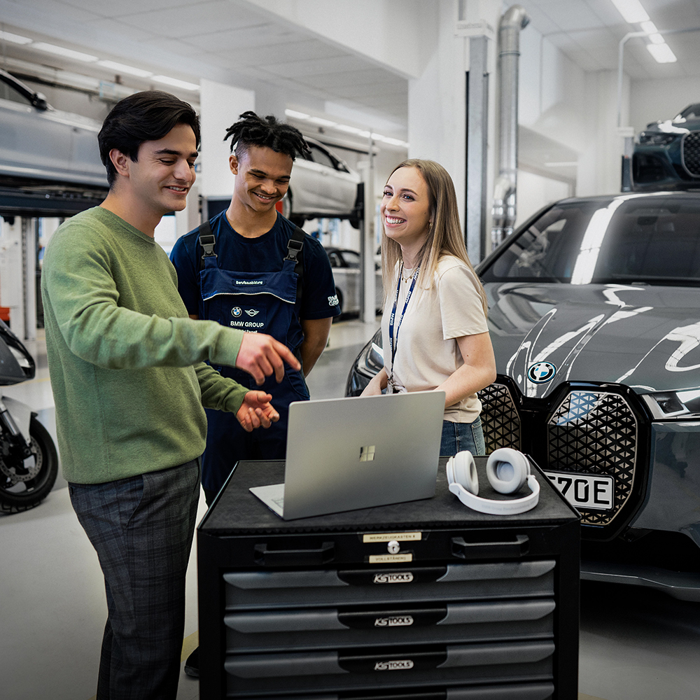 The photo shows three apprentices in a BMW work shop.