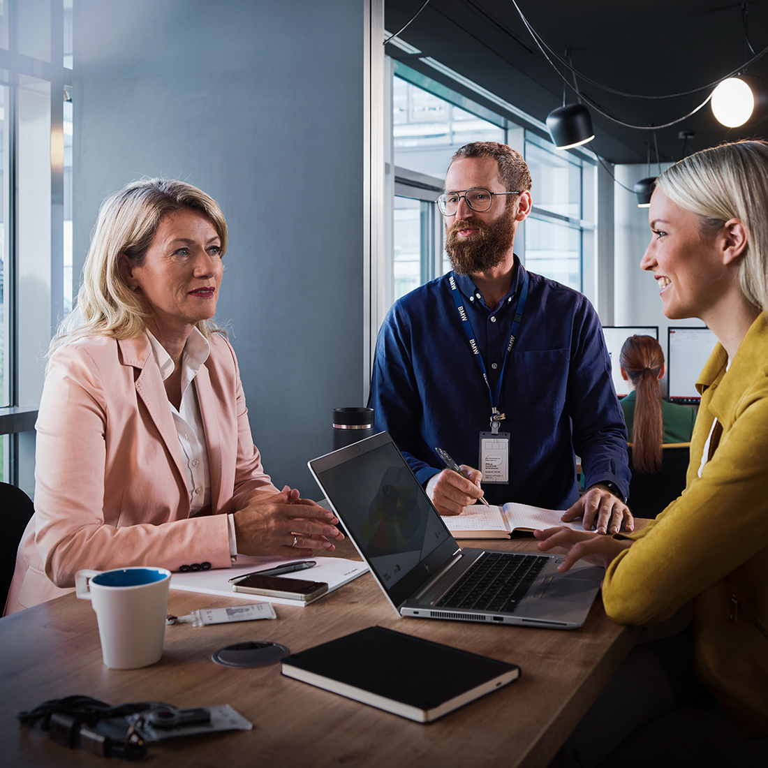 Three BMW professionals, two women and a man, are attending a meeting.