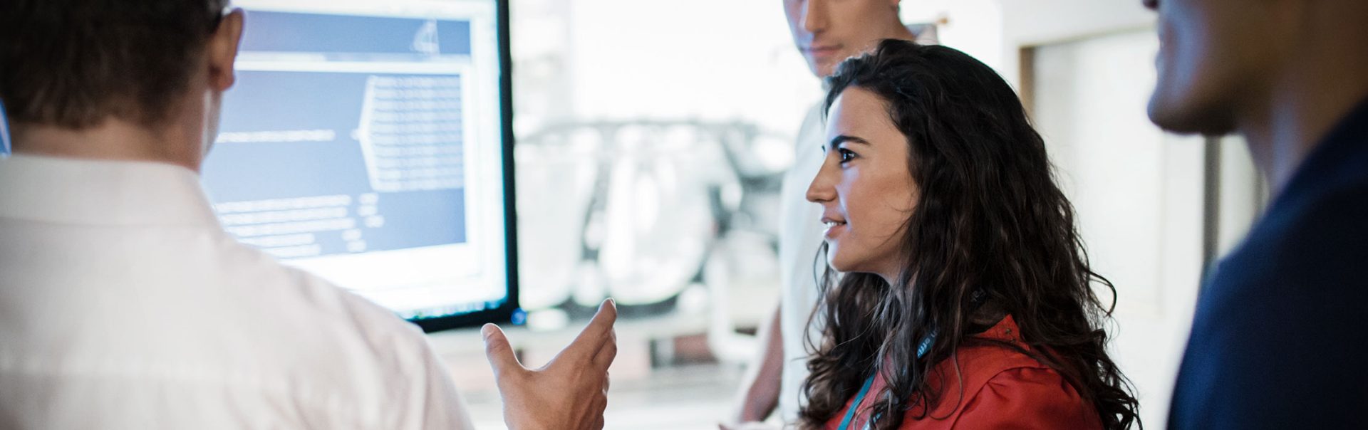 Four BMW employees standing in front of a graphic and discussing.