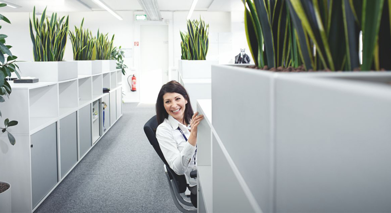 The picture shows a laughing BMW employee in an open office.