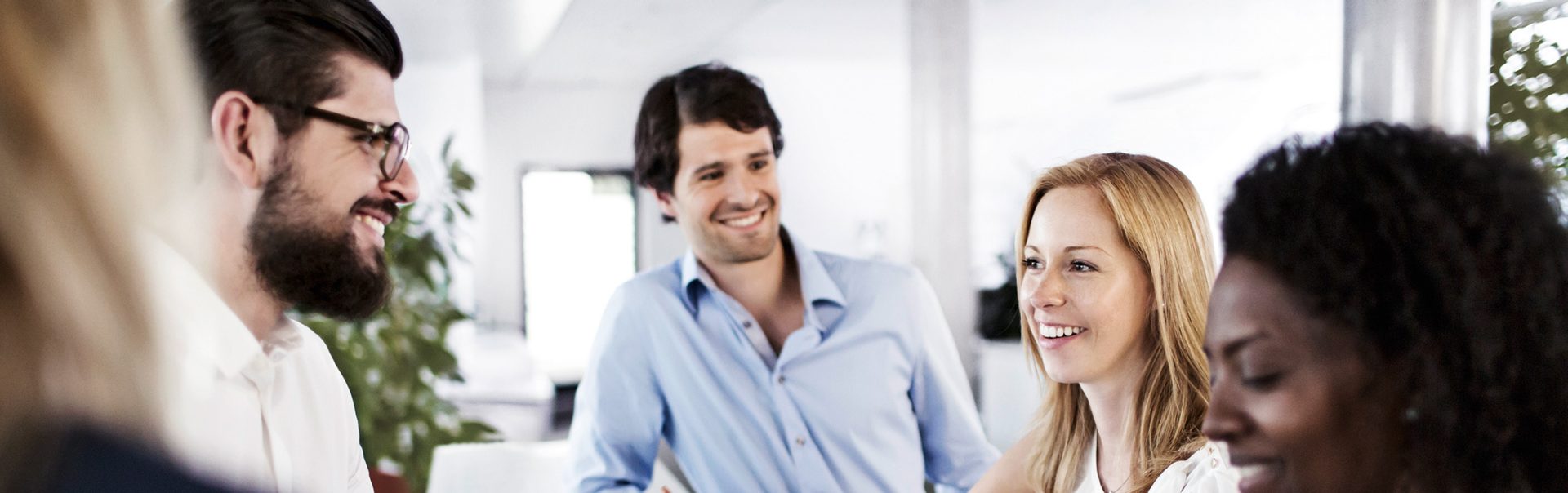 A group of five colleagues have a chat and laugh.