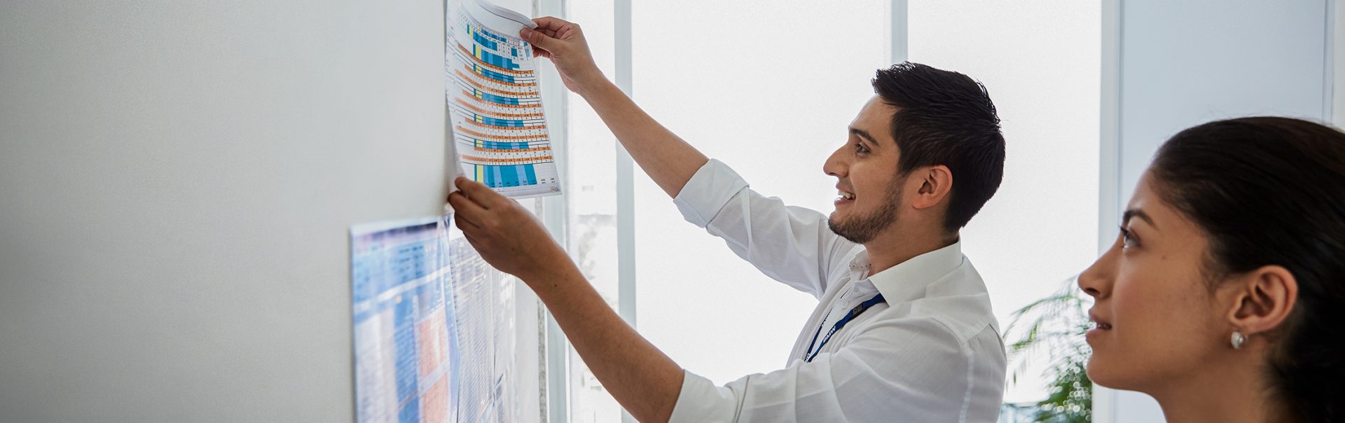 Two colleagues discuss data on a whiteboard.