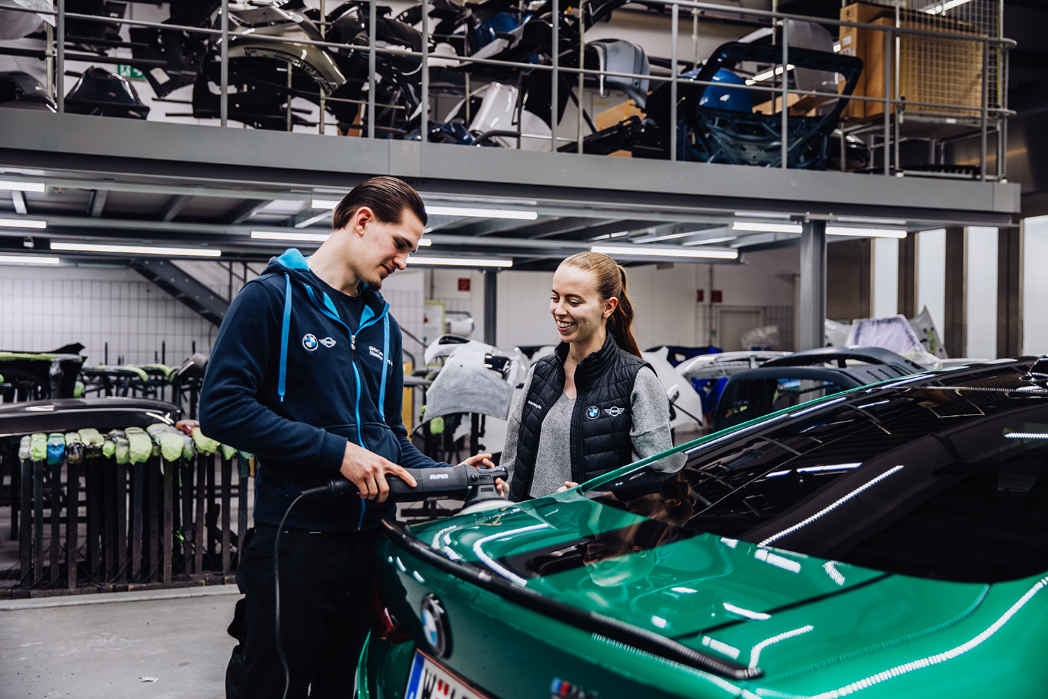 Karosseriebau-Lehrling mit Ausbilderin beim Polieren eines BMW M4