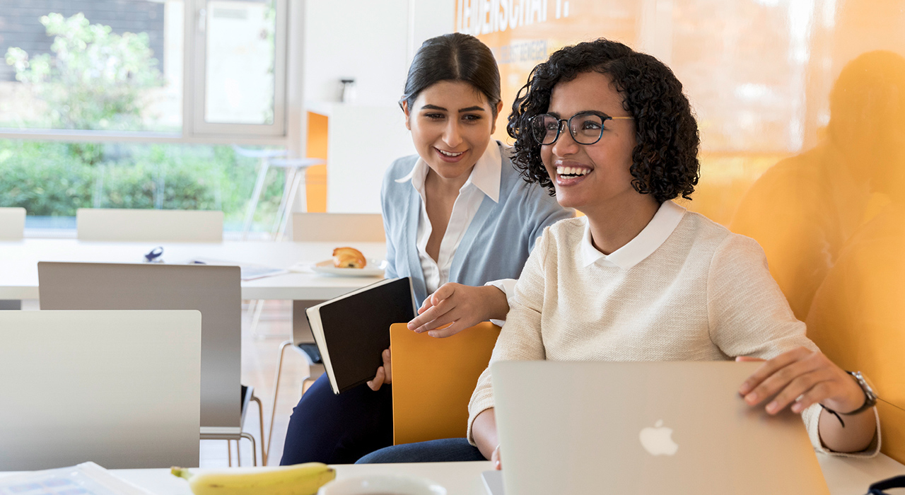 The picture shows two laughing young women representing the company culture at BMW.