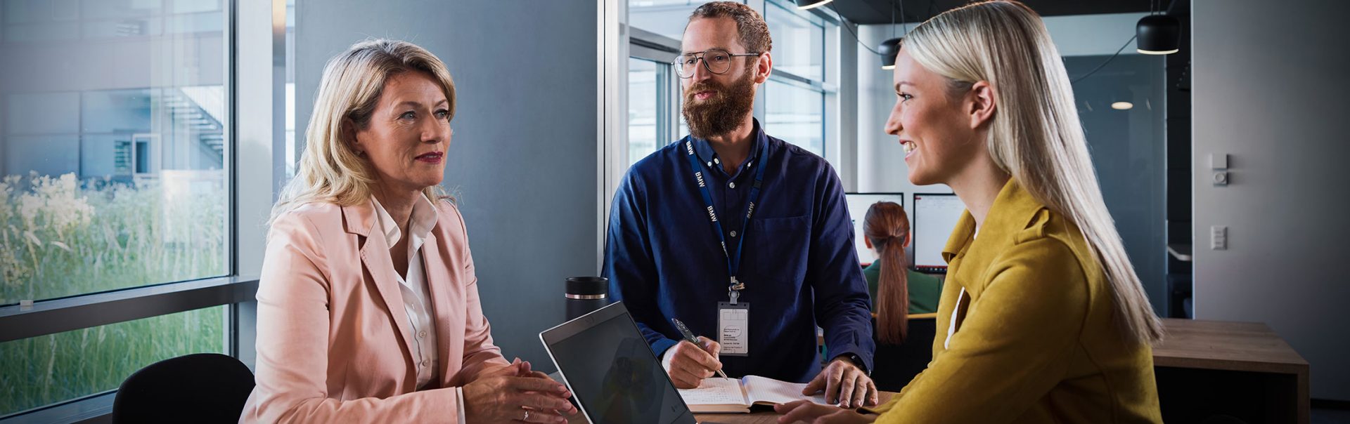 Three employees discussing in a meeting room.