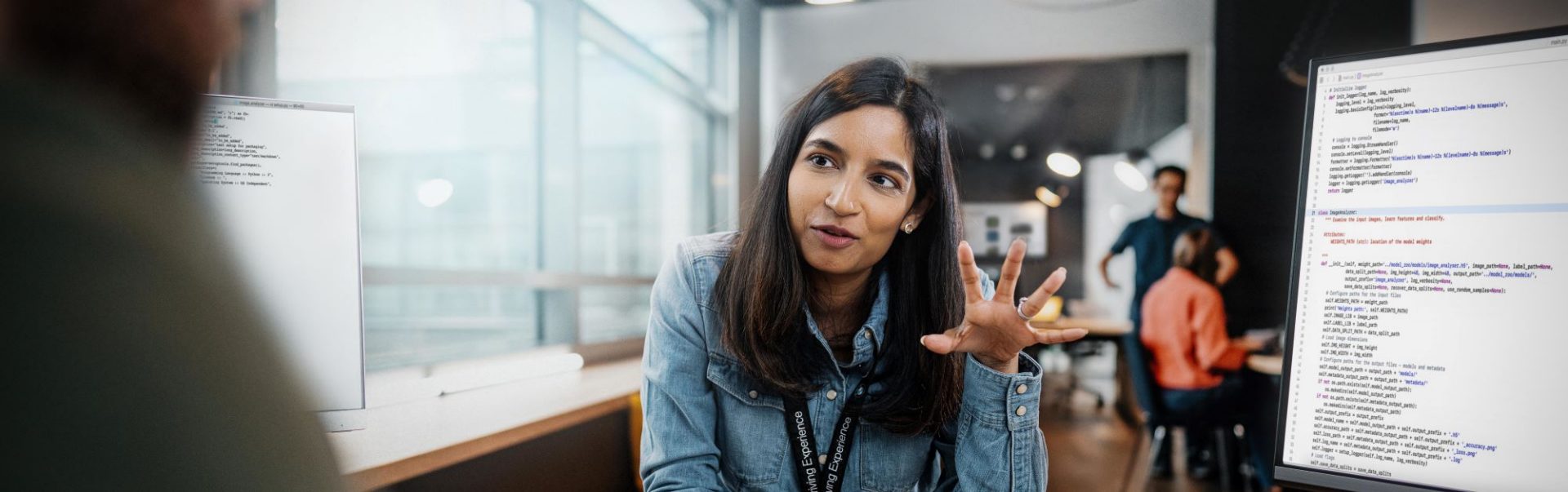 We see a young woman discussing something with someone in a modern office.