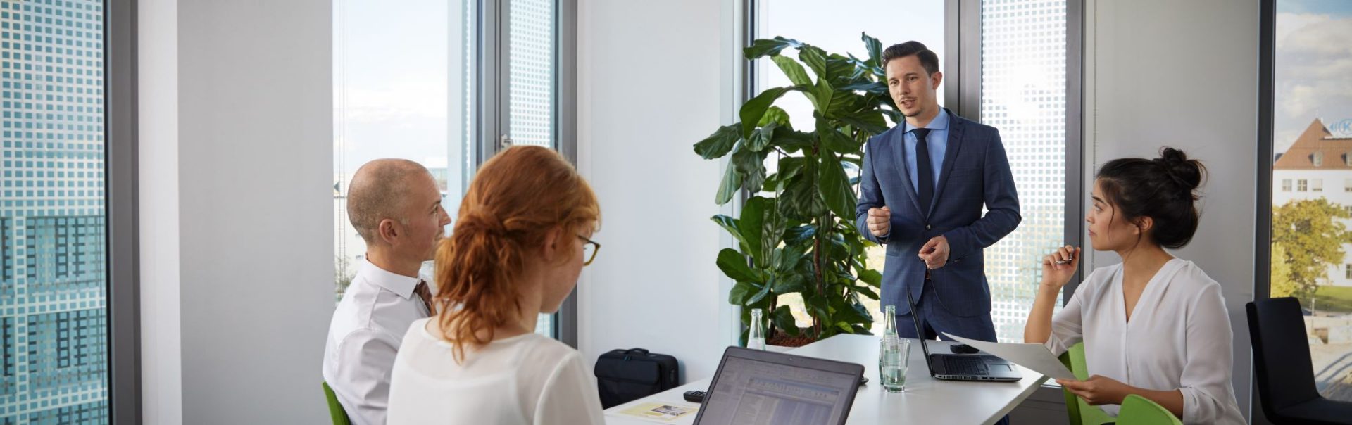 We see four young BMW employees having an animated conversation in a modern office.
