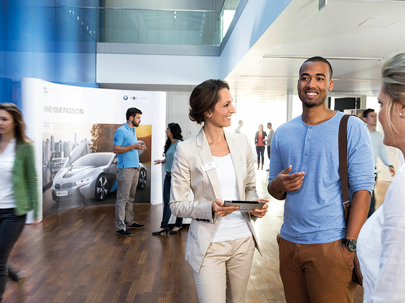 In this picture, a female professional explains the benefits of a BMW career to a young man.