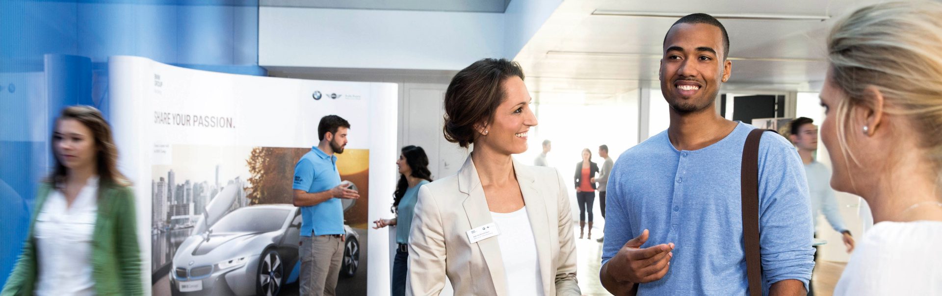 In this picture, a female professional explains the benefits of a BMW career to a young man.	