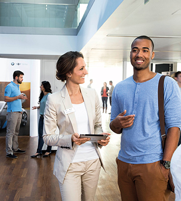 In this picture, a female professional explains the benefits of a BMW career to a young man.	