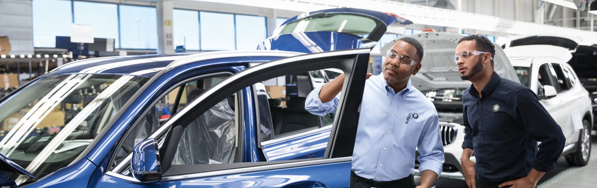 Two BMW employees checking the quality of a car. 