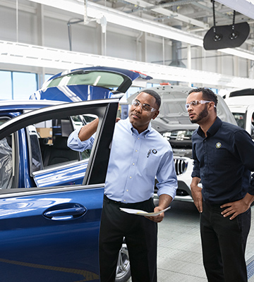 Two BMW employees checking the quality of a car. 