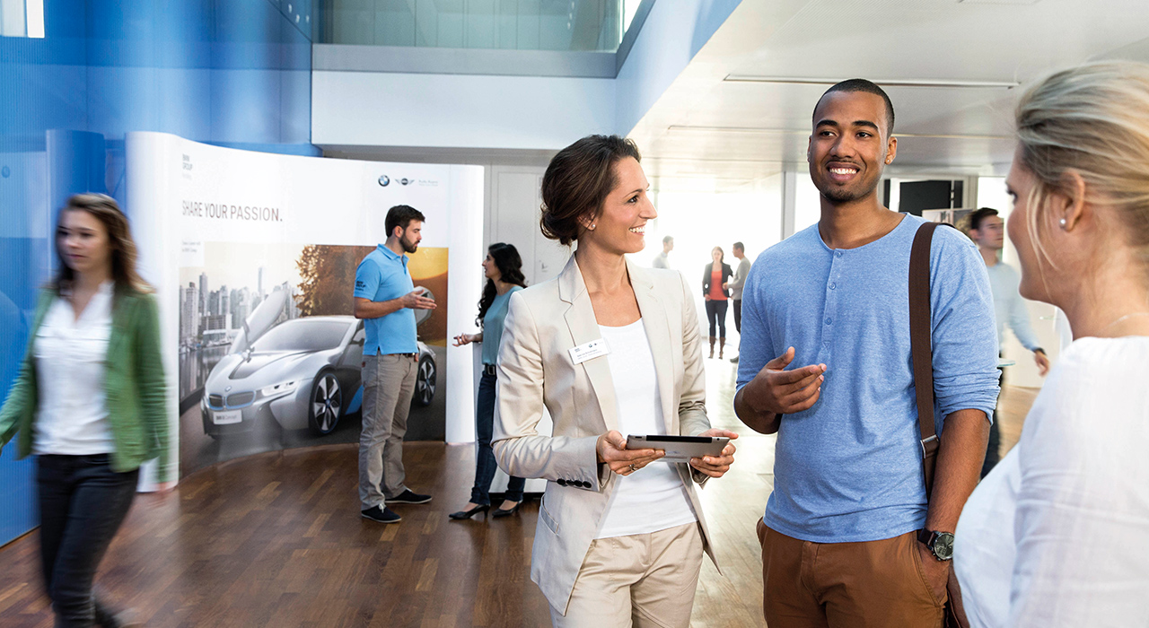 In this picture, a female professional explains the benefits of a BMW career to a young man.