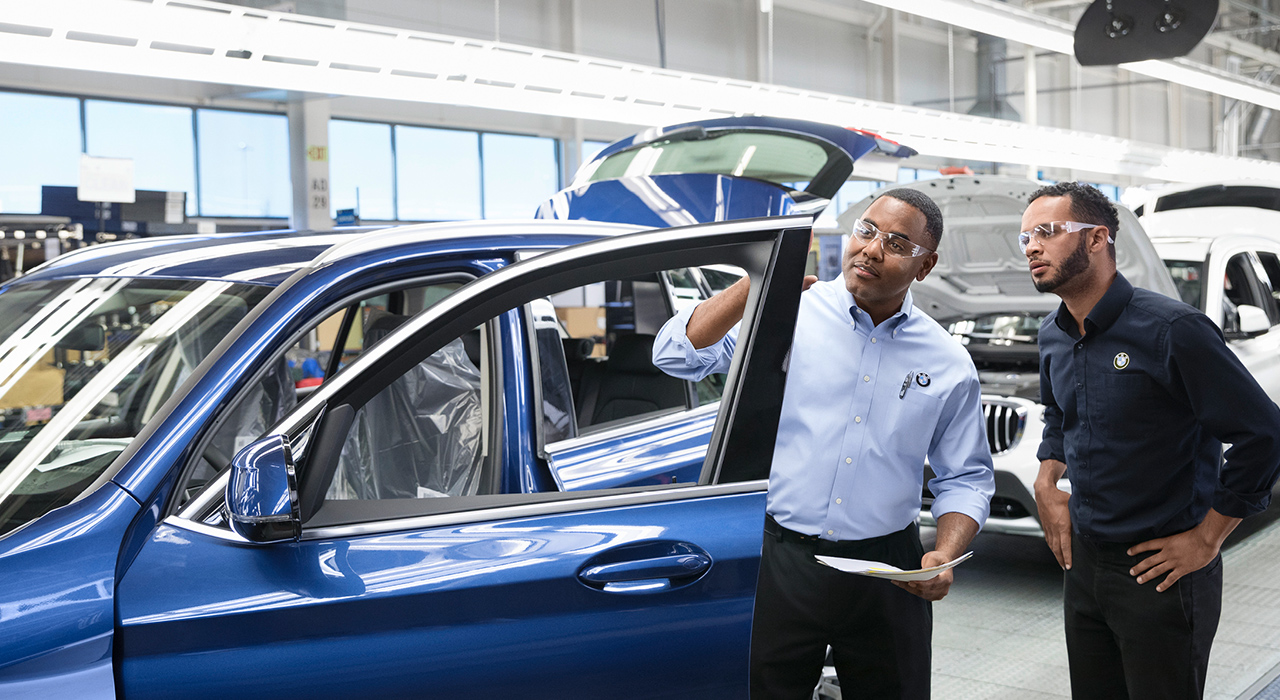 Two BMW quality managers are checking a car.