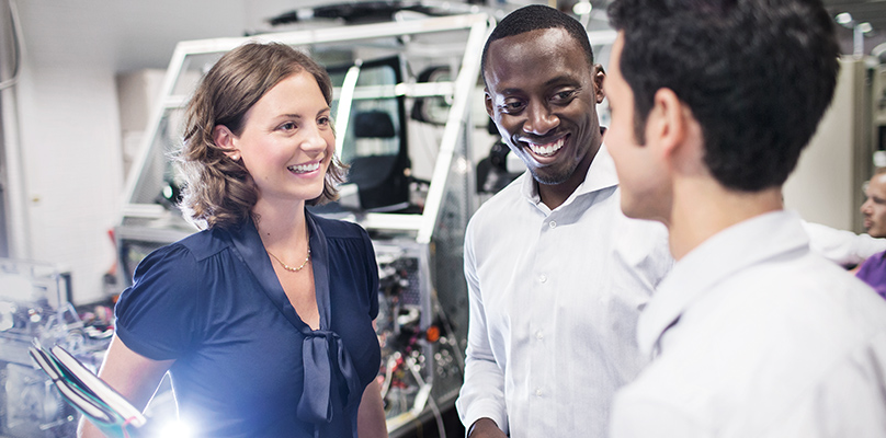 This photo shows three participants of the BMW graduate trainee program speaking to each other.