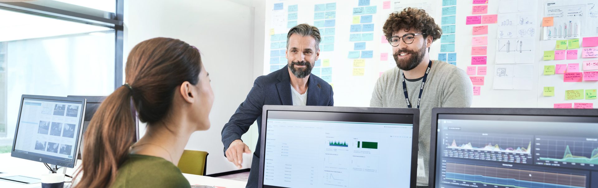 Three BMW professionals, a female one and two male ones, are meeting in an office to discuss a new project.