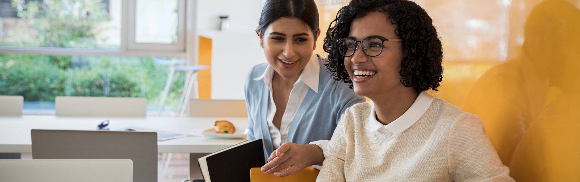 Two colleagues in a BMW canteen laugh and have a Chat.