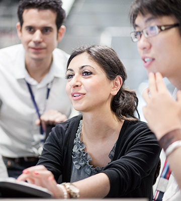 Three male students and a female student are looking at a computer.