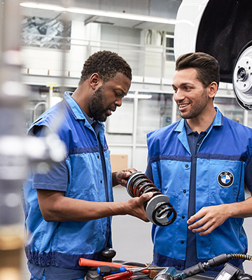 A imagem representa a cultura do trabalho, mostrando dois funcionários da produção da BMW.