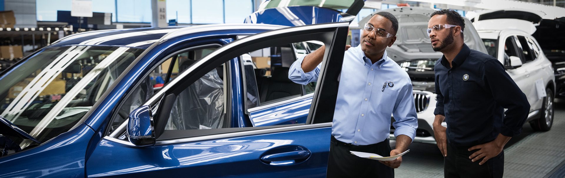 Dois gerentes de qualidade da BMW estão inspecionando um carro.