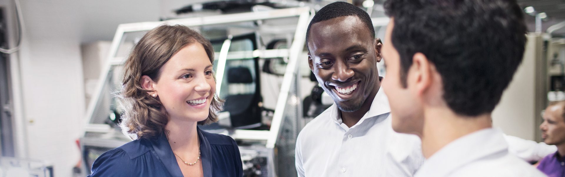 Esta foto mostra três participantes do programa de trainee da BMW conversando entre si.