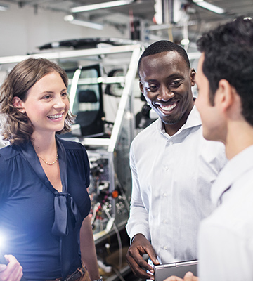 Esta foto mostra três participantes do programa de trainee da BMW conversando entre si.