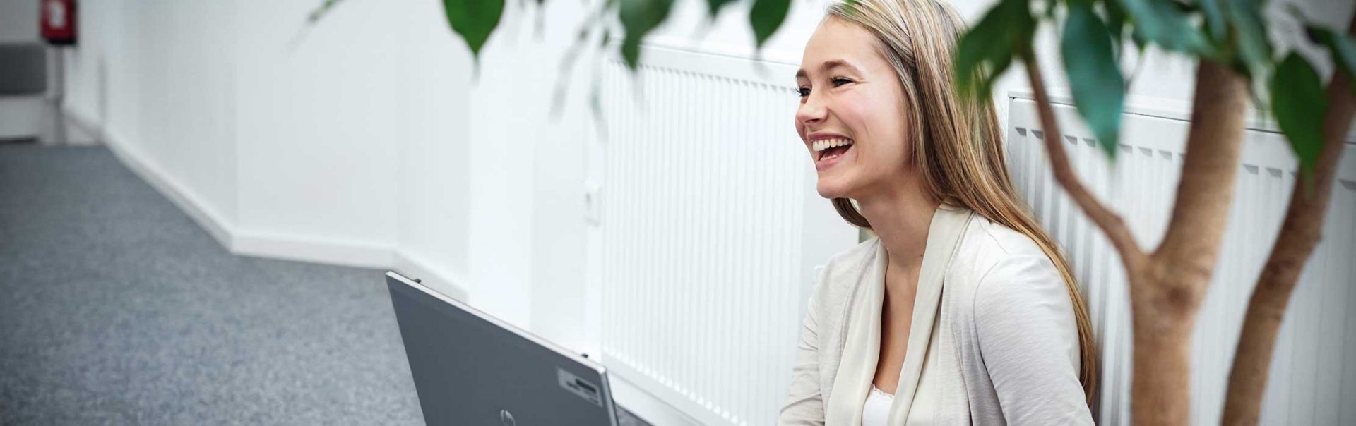 A young woman sitting on the floor working on her laptop