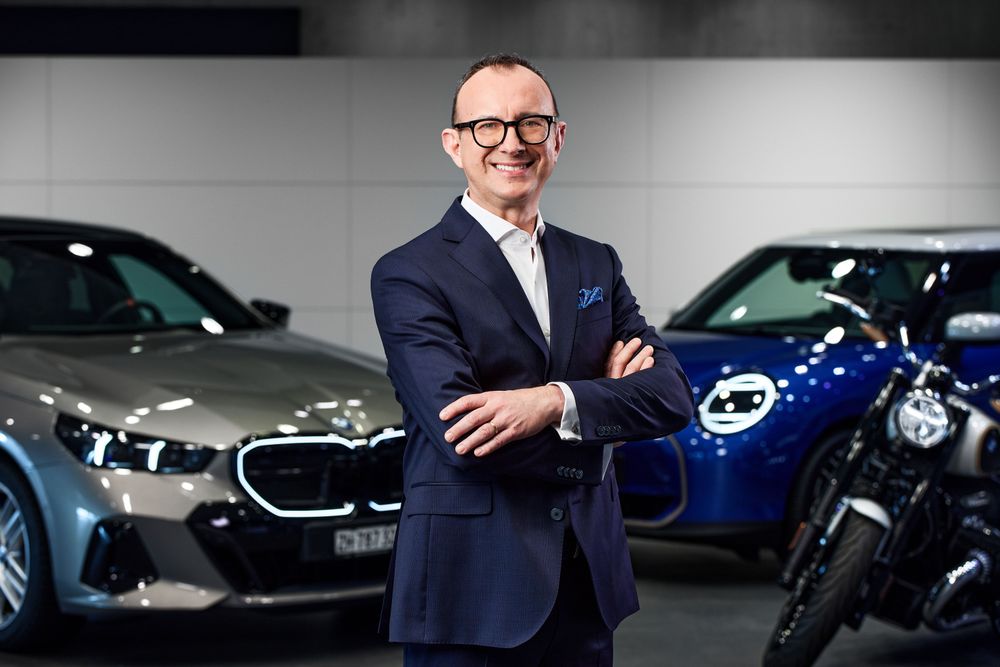 Sergio Solero, President of BMW Schweiz AG, standing between various BMW Group vehicles.