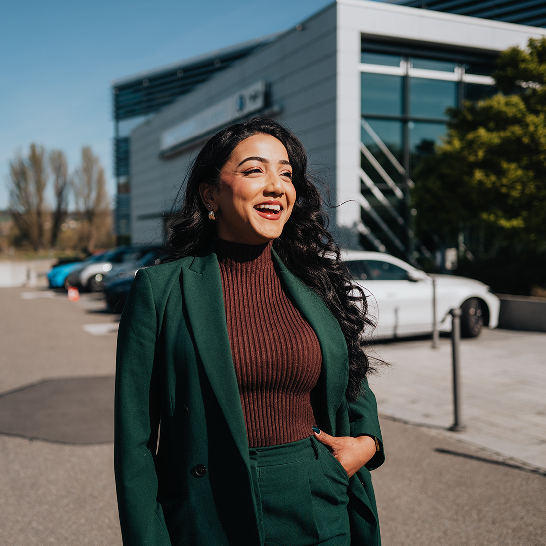BMW employee Mithursha in a green suit in front of the BMW Schweiz AG building