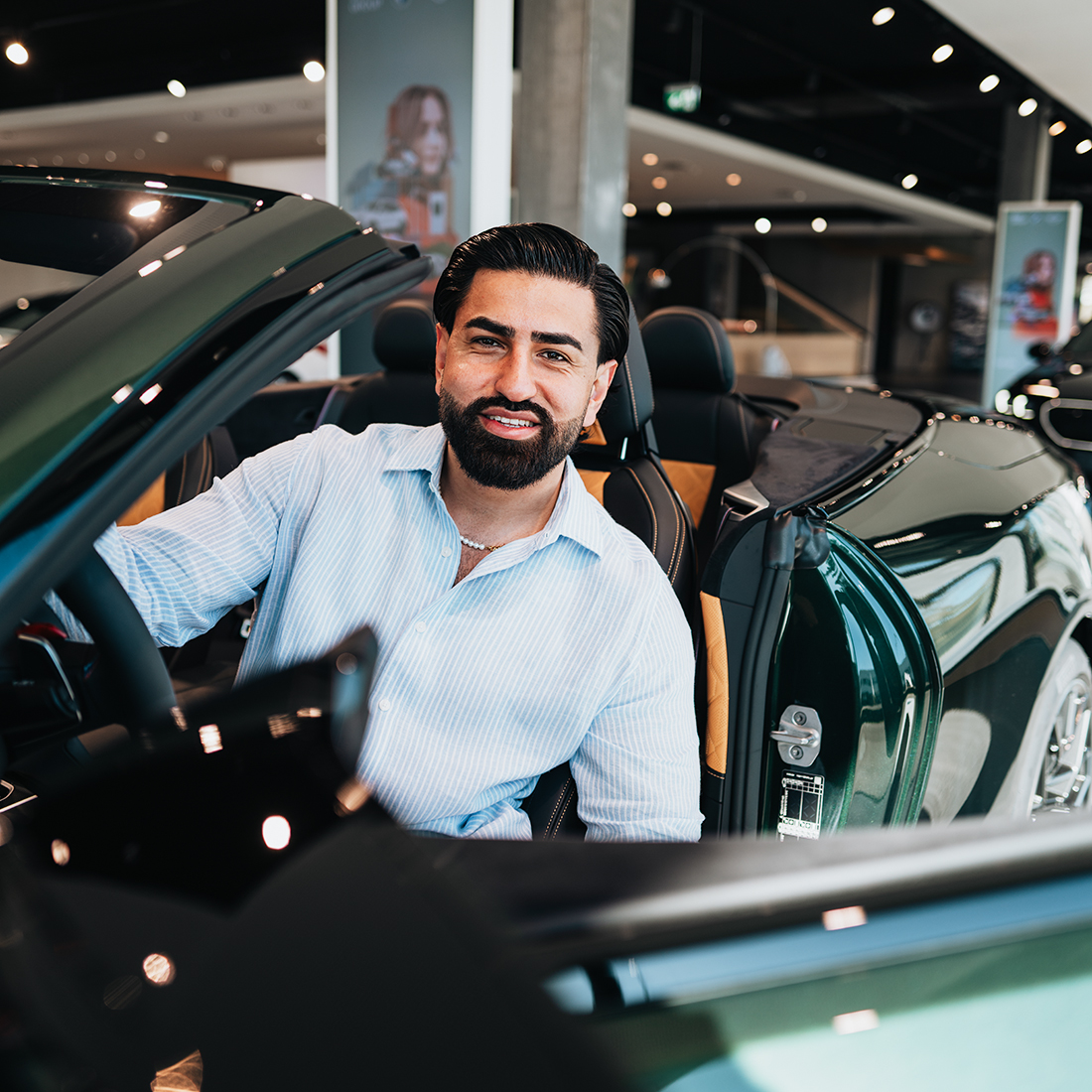 BMW Mitarbeiter Wali lächelnd in einem BMW M4 Cabrio