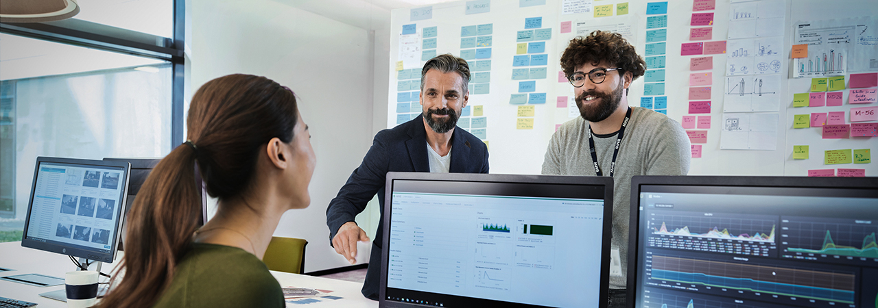 Three colleagues are having a conversation at their workplace.