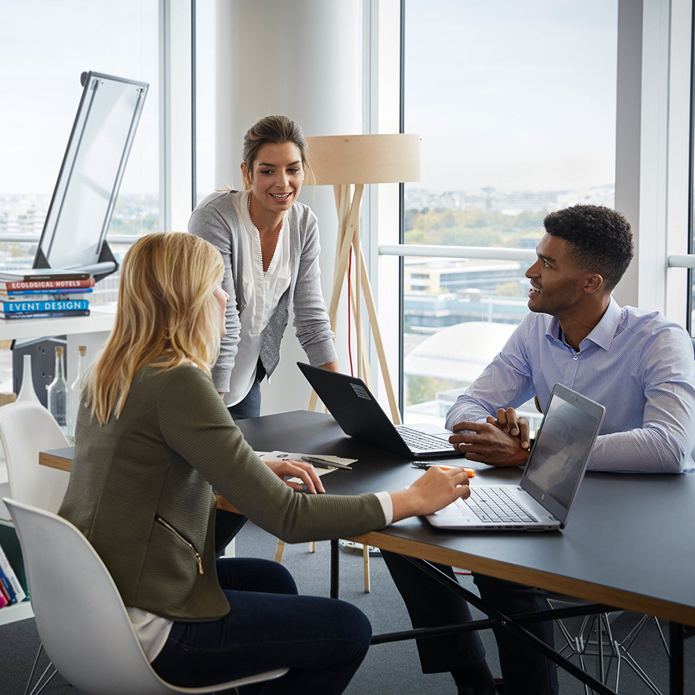 Three employees in compliance are sitting together having a conversation.